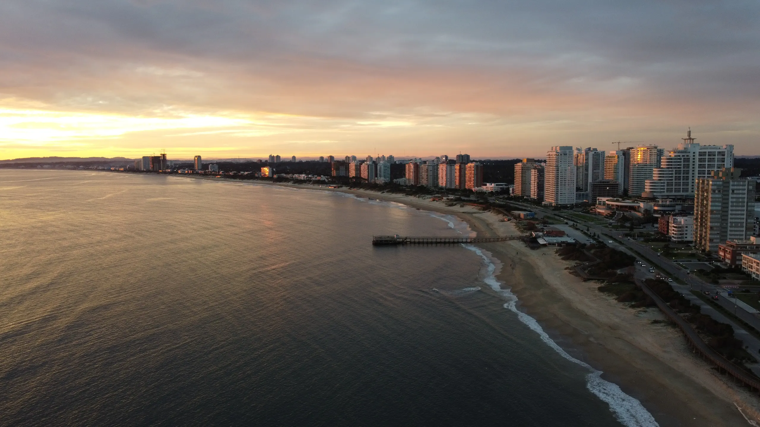 Playa Mansa bay at dusk, with the jetty and the line of towers along the shore