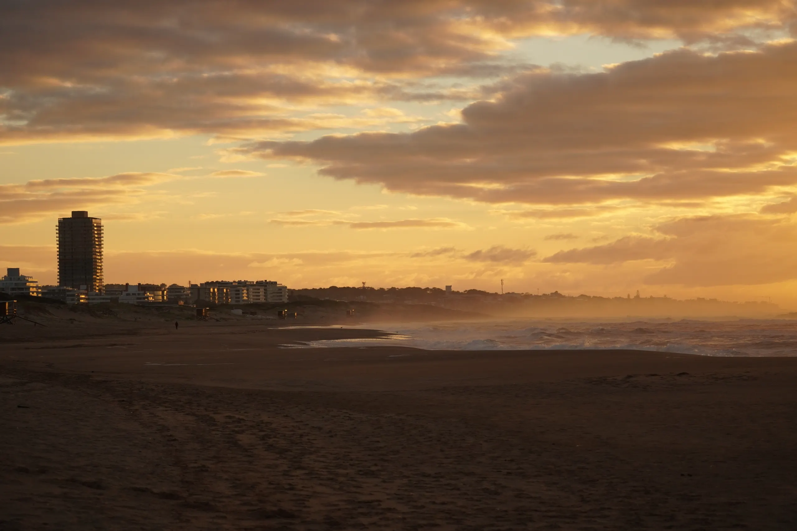 Dusk over a Punta del Este beach, with the city skyline on the horizon